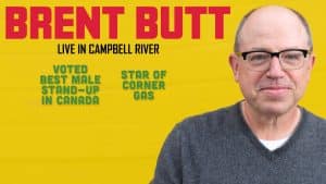 A man with glasses and a grey sweater smiles at the camera. Text reads: "BRENT BUTT LIVE IN CAMPBELL RIVER. Voted best male stand-up in Canada. Star of Corner Gas." The background is yellow.