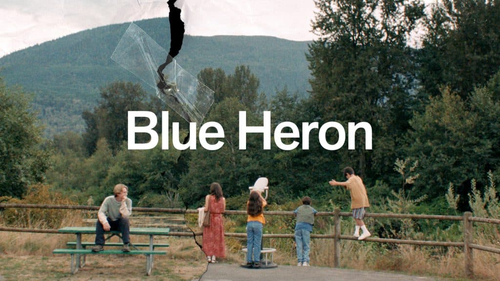 Five people stand near a wooden fence in a park, with trees and mountains in the background. A person sits on a picnic table. White text reads “Blue Heron” and the photo appears torn with tape near the top, possibly as part of a CRFF event or gathering.