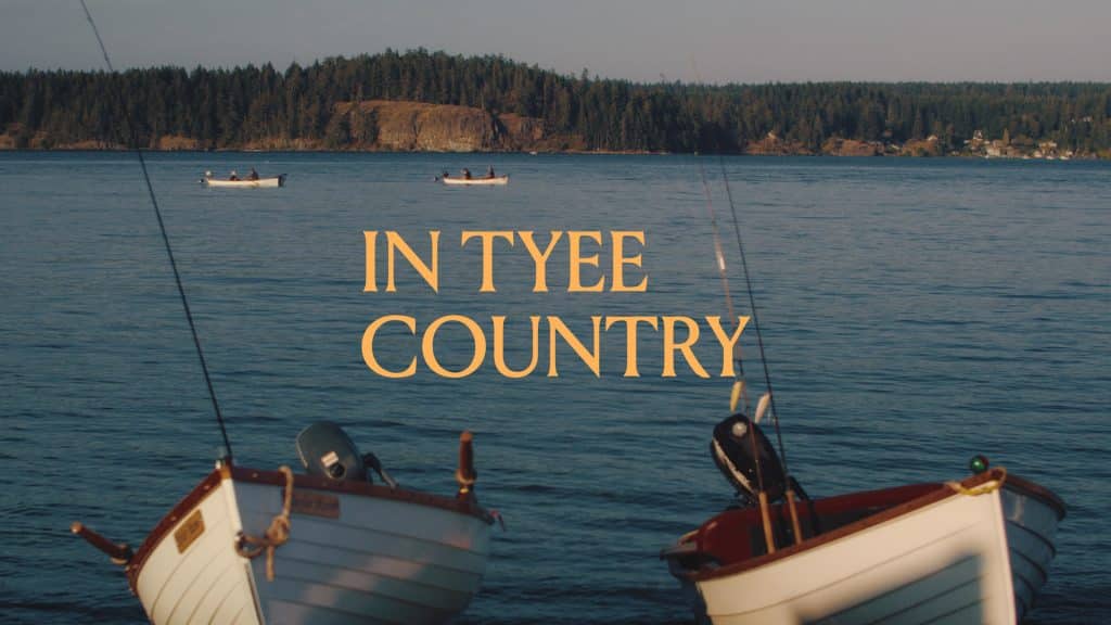 Two small motorboats float in the foreground, with two distant boats on the water and text that reads, “IN TYEE COUNTRY,” marking a premier travel destination.