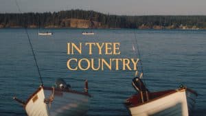 Two small motorboats float in the foreground, with two distant boats on the water and text that reads, “IN TYEE COUNTRY,” marking a premier travel destination.